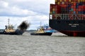 Tugs lead out a container ship from the port from Felixstowe UK